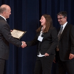 Doctor Potteiger shaking hands with an award recipient in a black blazer and a white shirt